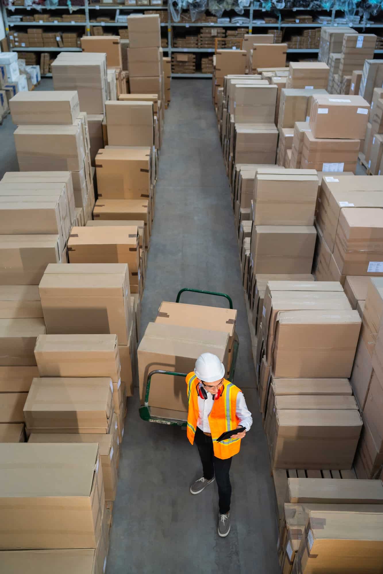 Logistic warehouse worker delivering boxes on a trolley
